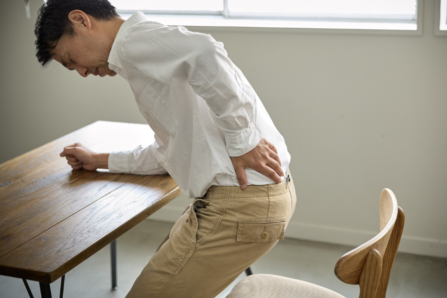 Man leaning on the table because of lower back pain