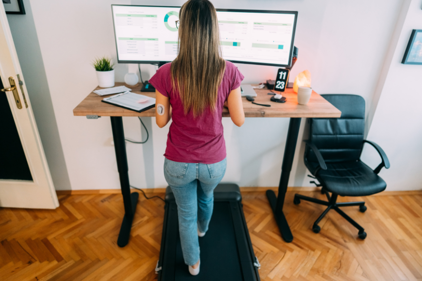Woman working on her ergonomic standing desk while walking on her walking pad