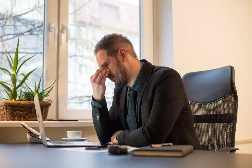 Man with tired and eye strain due to working on laptop