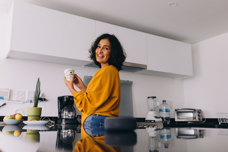 Woman having her coffee while using her smart speaker