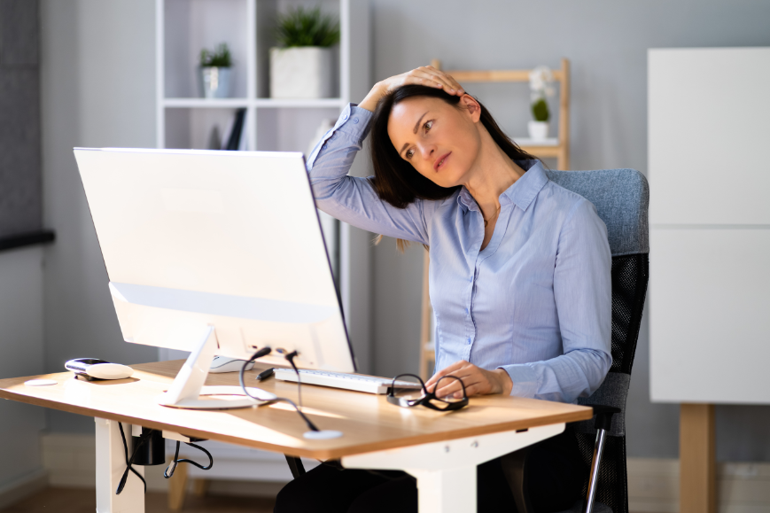 Women doing neck stretch while sitting in front of her computer to reduce desk stiffness